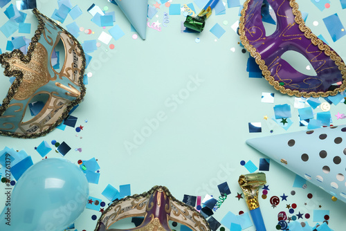 Frame of beautiful carnival masks and party decor on light blue background  flat lay. Space for text