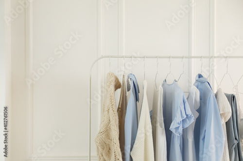 Rack with stylish women's clothes near white wall. Interior design