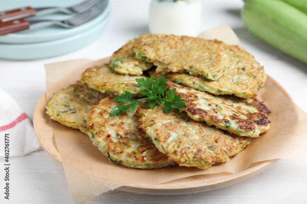 Delicious zucchini fritters served on white wooden table, closeup