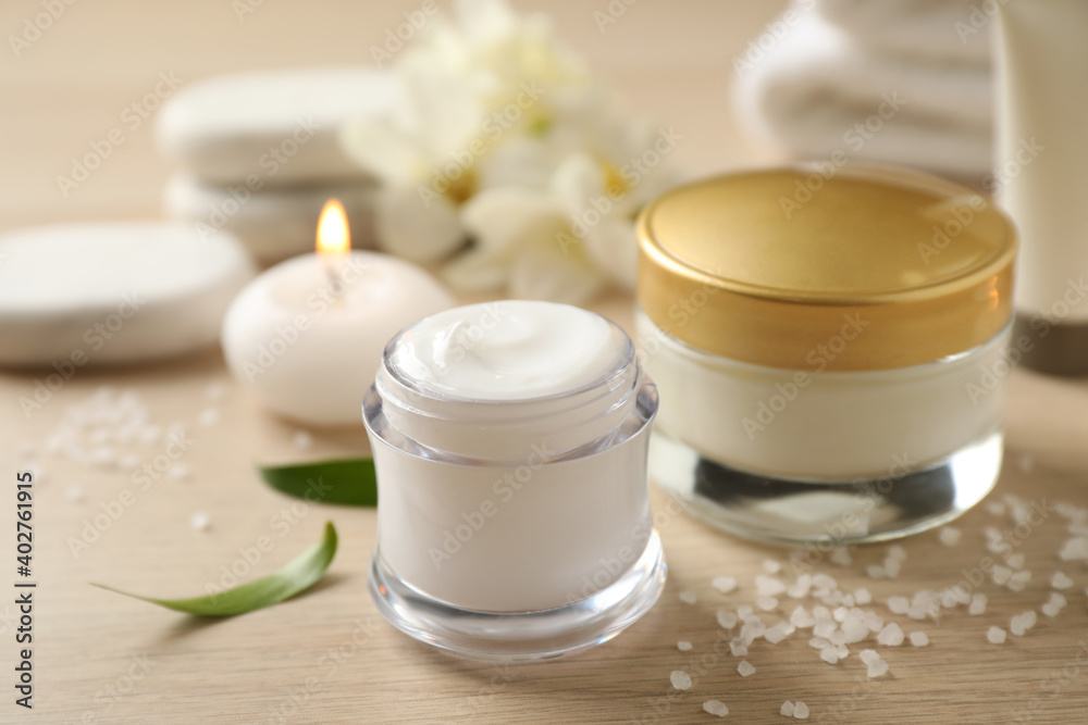 Composition with skin care products and candle on wooden table, closeup