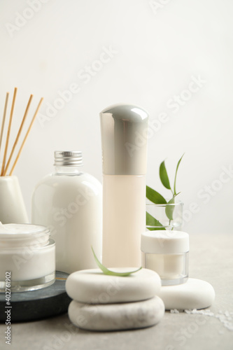 Composition with skin care products and spa stones on light background, closeup