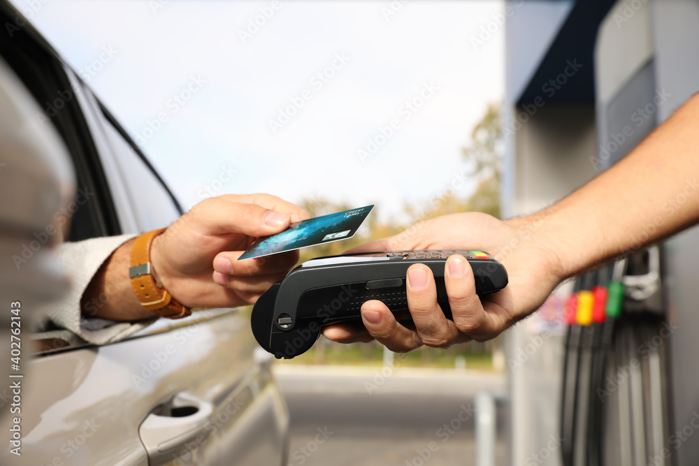 Man sitting in car and paying with credit card at gas station, closeup Man sitting in car and paying with credit card at gas station, closeup