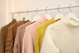 Rack with stylish warm clothes indoors, closeup