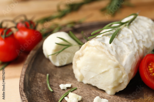 Delicious goat cheese with rosemary on wooden board, closeup