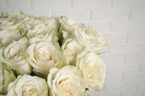 Luxury bouquet of fresh roses near white brick wall  closeup