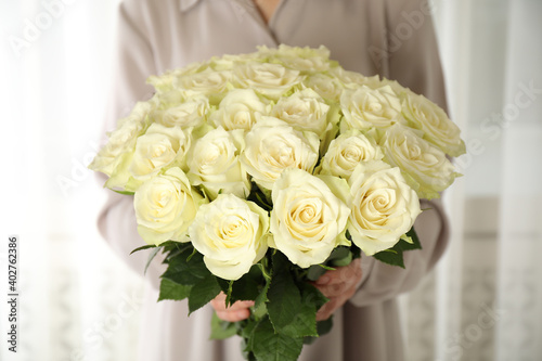 Woman holding luxury bouquet of fresh roses indoors  closeup