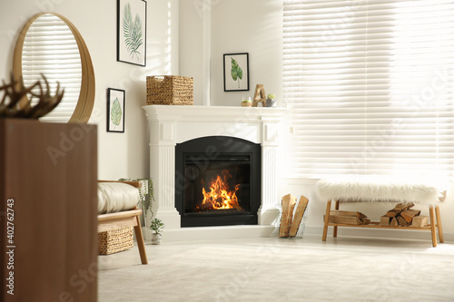 Fototapeta Bright living room interior with artificial fireplace and firewood
