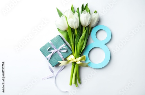 8 March greeting card design with tulips and gift on white background, top view