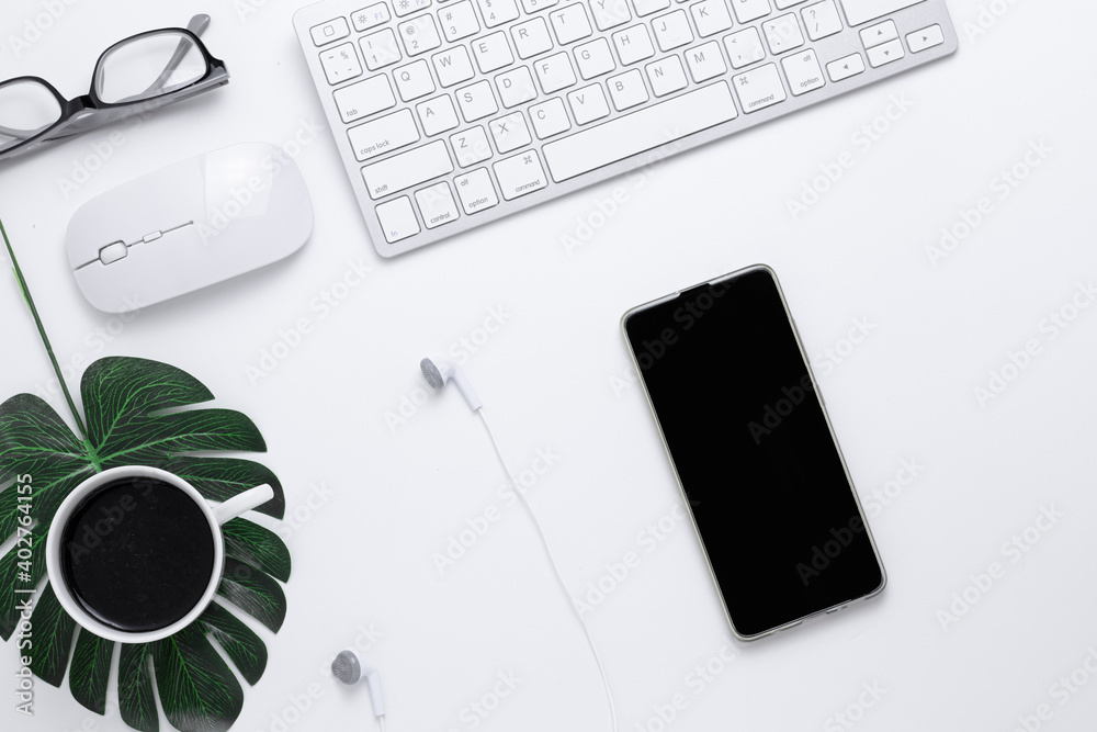 Minimal Office desk table top view with Smart phone, Earphones, Keyboard computer, mouse, Glasses, coffee cup on a white table with copy space, White color workplace composition, flat lay Minimal Office desk table top view with Smart phone, Earphones, Keyboard computer, mouse, Glasses, coffee cup on a white table with copy space, White color workplace composition, flat lay