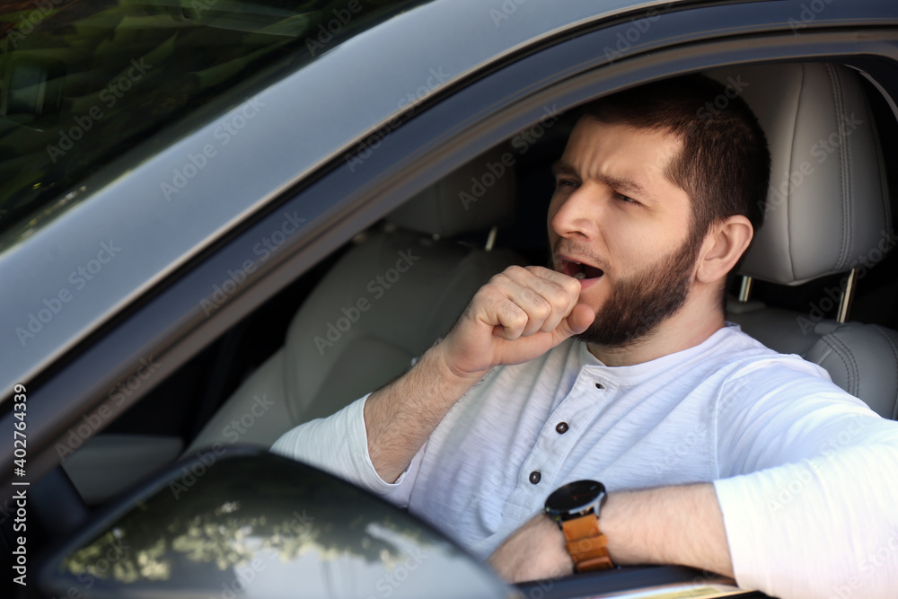 Tired man yawning in his modern car Tired man yawning in his modern car