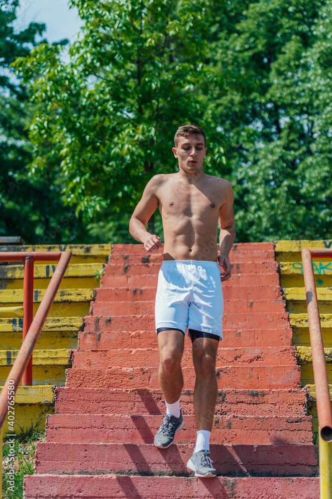 Obraz premium Sexy topless athlete running down the stairs in a park on a summer day