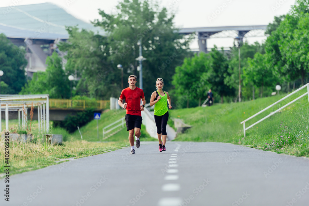 Young running couple jogging on an asphalt road in the park Young running couple jogging on an asphalt road in the park