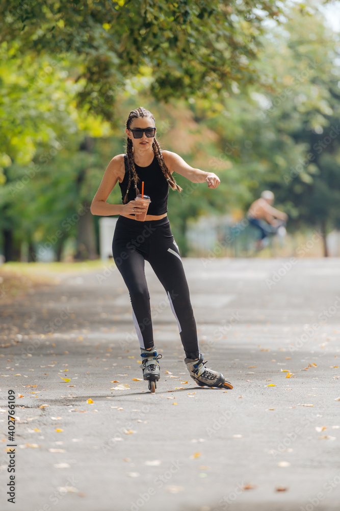 Hot athletic woman in sportswear rollerblading at the park in sunny weather.. Hot athletic woman in sportswear rollerblading at the park in sunny weather..