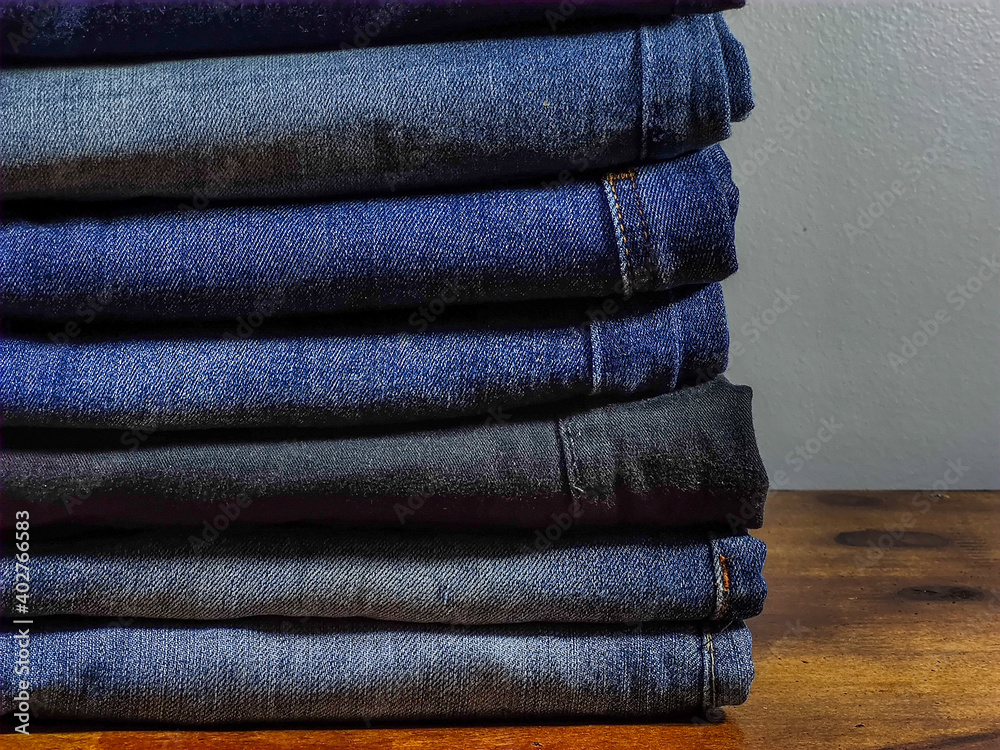Beauty and fashion, clothing concept. Jeans stacked on wooden table with gray background Beauty and fashion, clothing concept. Jeans stacked on wooden table with gray background