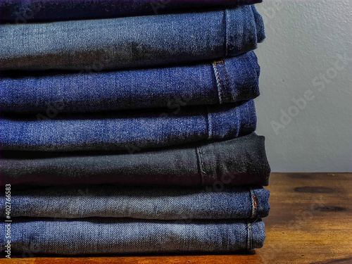 Beauty and fashion, clothing concept. Jeans stacked on wooden table with gray background