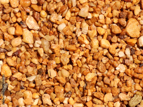 Gravel texture. Small stones, little rocks, pebbles in many shades of grey, white, brown, yellow colour. Background of small wet stones in oval shape. Texture of little rocks from river or lake.