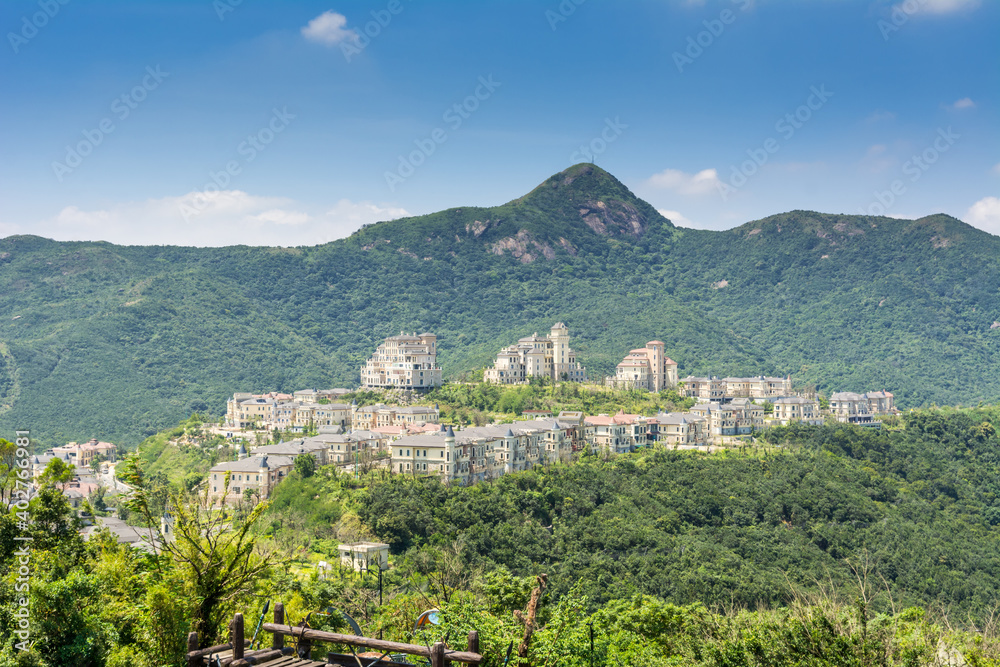 Obraz premium Modern castles on the top of mountain against cloudy sky in Overseas Chinese Town East (OCT East ) in Shenzhen, Guangdong, China.