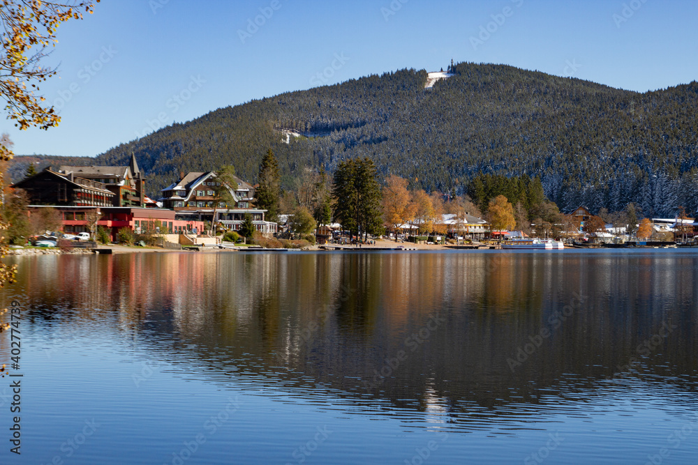 Fototapeta premium Titisee-Neustadt, Germany - 10 30 2012: surroundings of Titisee, european village in beautiful winter cold day. Scenery is reflected in the lake. 