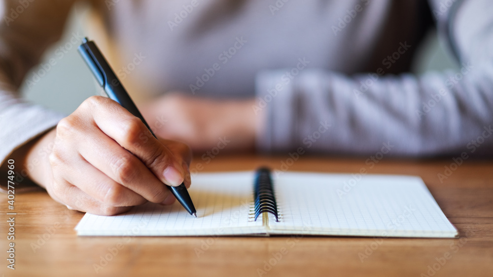 Closeup image of a woman writing on a blank notebook on the table Closeup image of a woman writing on a blank notebook on the table