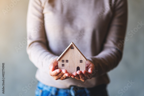 Closeup image of a woman holding and showing wooden house model © Farknot Architect