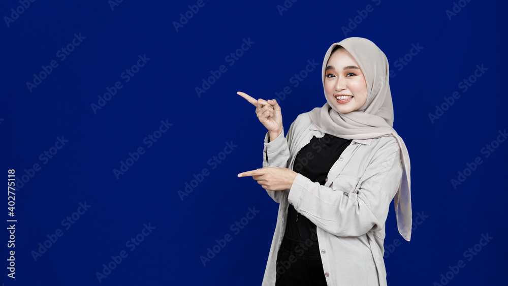 Asian hijab woman pointing left blank space isolated blue background Asian hijab woman pointing left blank space isolated blue background