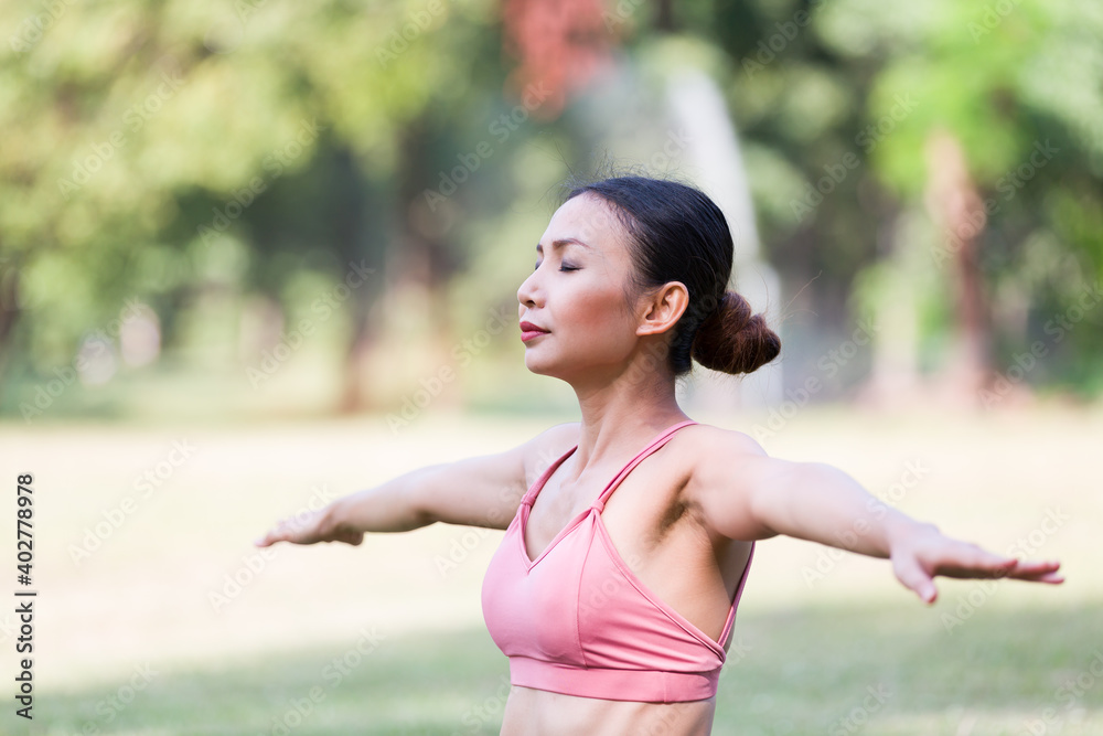 Asian woman practicing yoga outdoor in the park. Woman in sportswear doing yoga and stretching arms. Woman working out outdoor. Yoga and exercise outdoor concept Asian woman practicing yoga outdoor in the park. Woman in sportswear doing yoga and stretching arms. Woman working out outdoor. Yoga and exercise outdoor concept