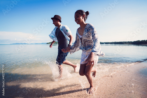 Asian teenage girl and boy running on the beach