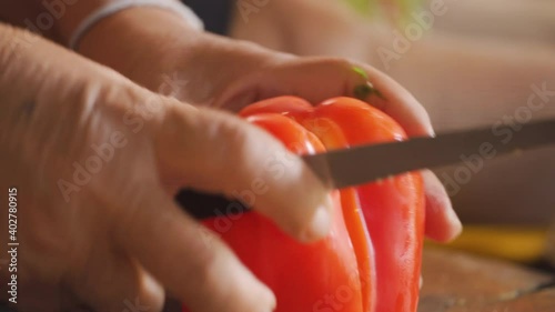 Sweet pepper in red color get slicing by old asian lady. Homemade barcecue at kitchen and preparing ingredient. Macro shot. photo