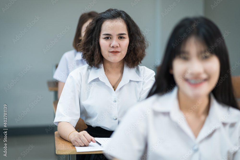 Portrait of cheerful Asian female college students writing and studying in the classroom. Selective focus teenage university students studying in classroom. Portrait of cheerful Asian female college students writing and studying in the classroom. Selective focus teenage university students studying in classroom.