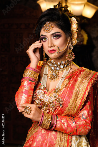 Картината върху платно Portrait of very beautiful young Indian bride in luxurious bridal costume with makeup and heavy jewellery in studio lighting indoor