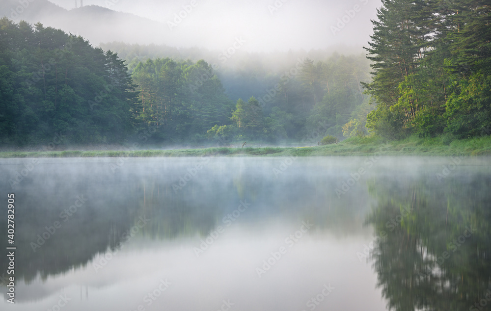 朝日と霧の漂う美しい夏の湖