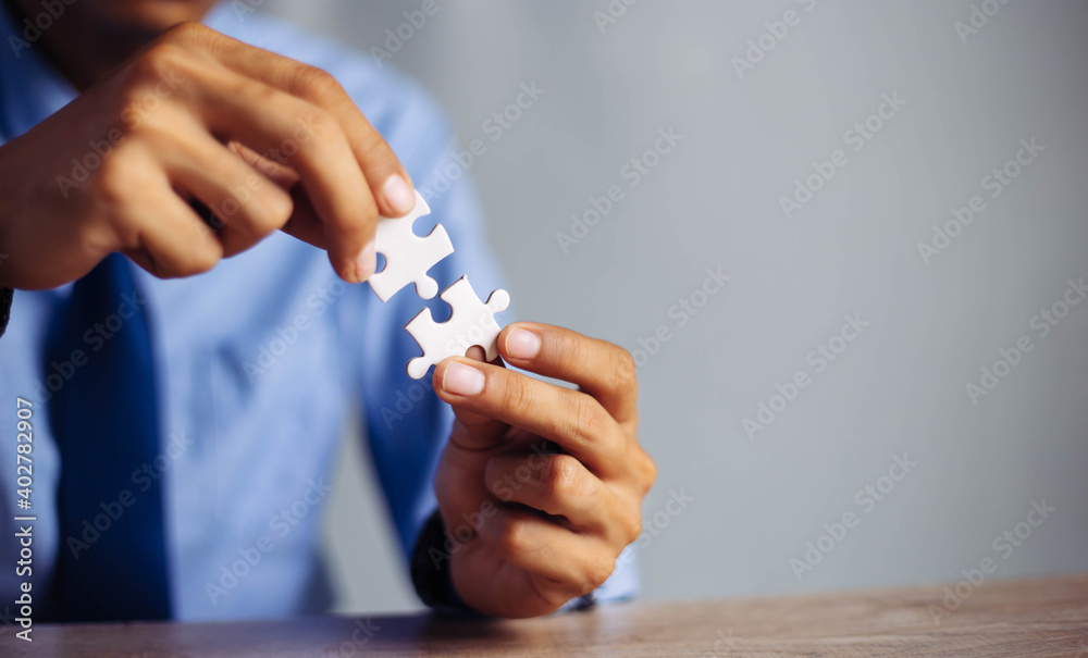 Closeup hand of man connecting jigsaw puzzle with sunlight effect, Business solutions, success and strategy concept Closeup hand of man connecting jigsaw puzzle with sunlight effect, Business solutions, success and strategy concept