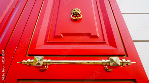 Seoul, South Korea - November 7, 2020: Close up of a bronze Chinese Lion head door knocker and handle on bright red shopping shop Imvely's door in Hongdae (Hongik University) street. photo