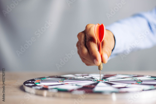 Businessman holding a darts aiming at the target center business goal concept - business targeting, aiming, focus concept,metaphor to target marketing or target arrow to business successconcept. photo