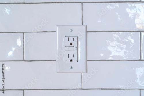 Three slot grounded receptacle for appliances against white tile wall of home photo
