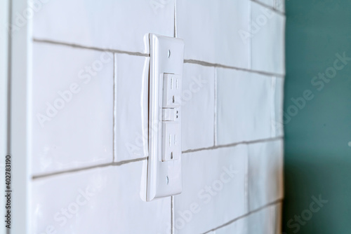 Home interior with close up view of a grounded outlet installed on the tile wall