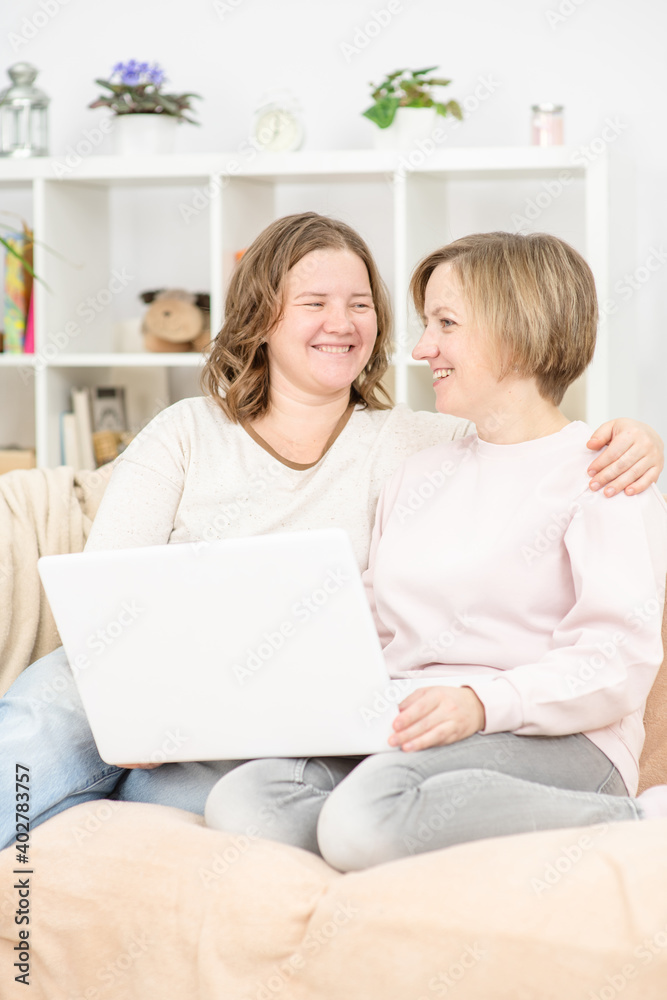 Beautiful young women LGBT lesbian happy couple sitting on sofa using laptop a computer in living room at home. LGBT lesbian couple together indoors concept. Beautiful young women LGBT lesbian happy couple sitting on sofa using laptop a computer in living room at home. LGBT lesbian couple together indoors concept.