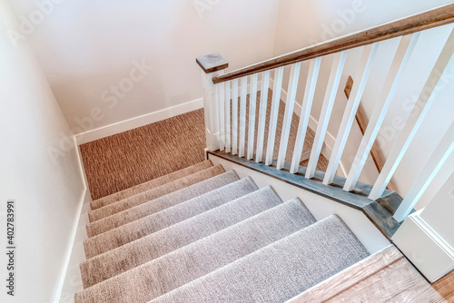 Fotobehang Interior staircase with U shaped design wooden handrail and carpet on treads