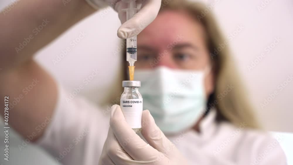 selective focus clip of a female health care worker drawing a vaccine from vial prior to a it being injected