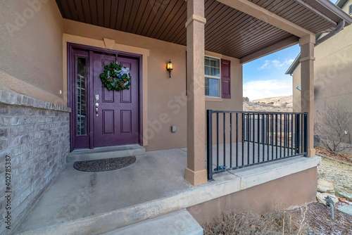 Vibrant purple front door with sidelight and wreath at the facade of home