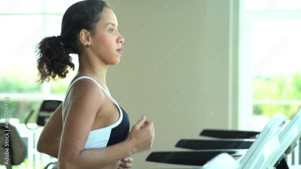 Attractive young sports woman running on a treadmill in fitness gym indoors. runner girl in sportswear workout or training on running machine in sport club