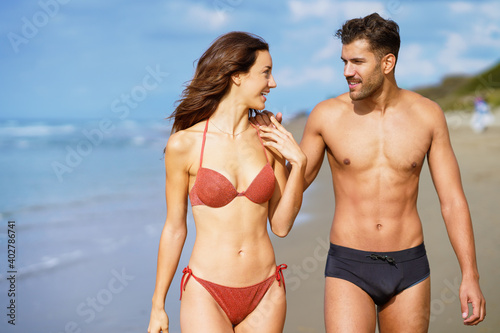 Young couple of beautiful athletic bodies walking together on the beach