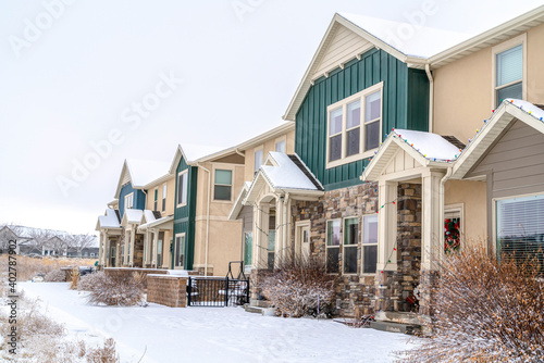 Apartment on snowy neighborhood with Christmas lights and wreaths at the facade