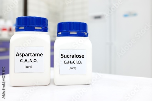 Selective focus of a bottle of pure aspartame and sucralose artificial sweetener sugar substitute chemical compound comparison. White laboratory background with copy space.