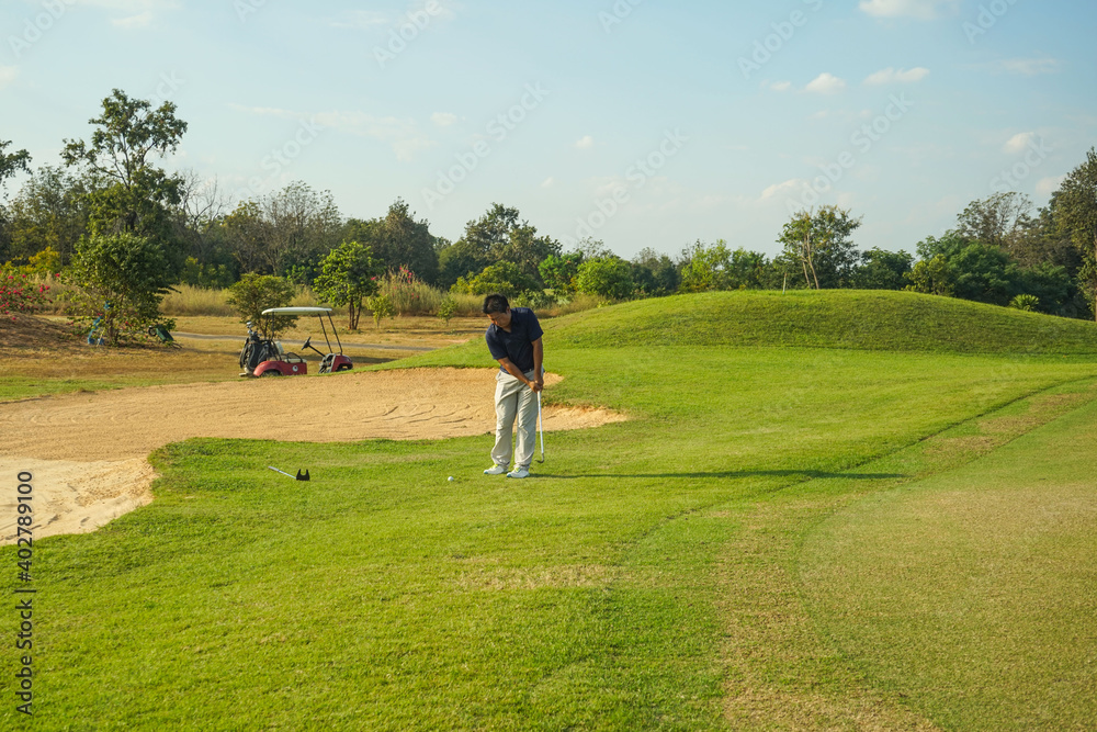 Golfer playing golf in the evening golf course, on sun set evening time. Man playing golf on a golf course in the sun. Golfer playing golf in the evening golf course, on sun set evening time. Man playing golf on a golf course in the sun.
