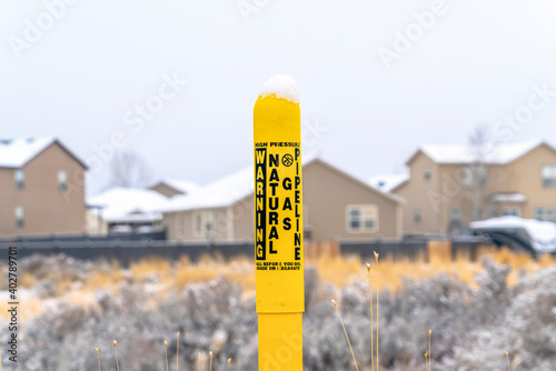 Pole marker with warning sign for natural gas pipeline buried underground