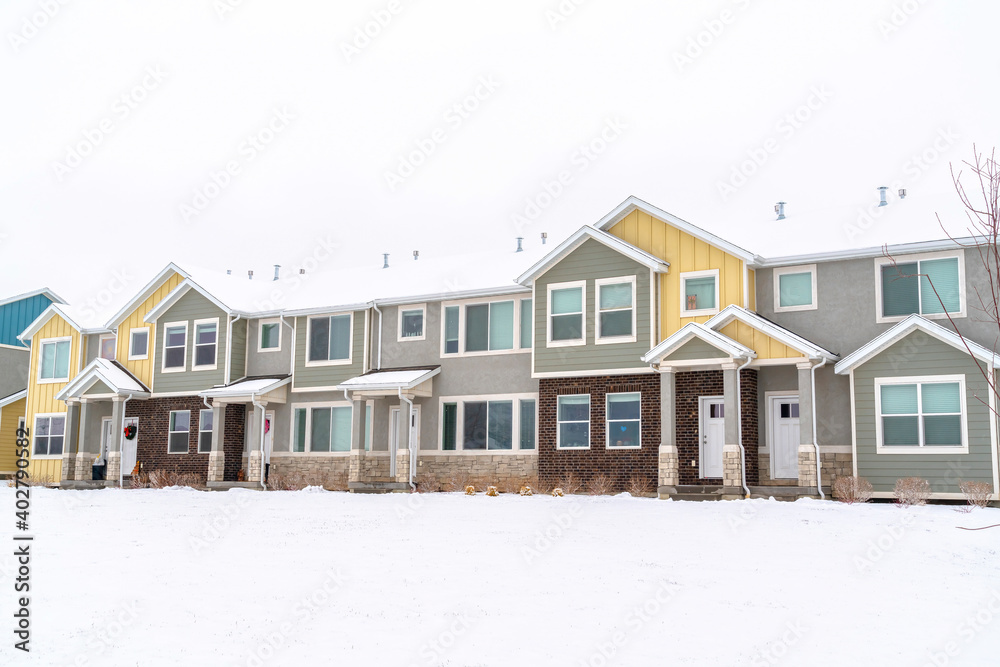 Apartment houses in a snowy neighborhood with cloudy sky background in winter Apartment houses in a snowy neighborhood with cloudy sky background in winter