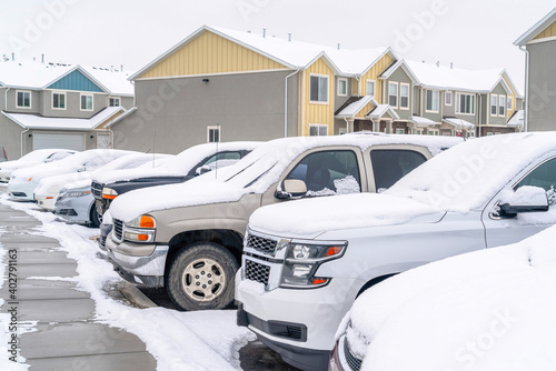 Cars in the parking lot of a neighborhood against homes and apartments in winter