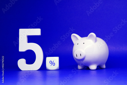 Five Percentage ( 5% ) word with piggy bank Isolated on blue Background with Copy Space , Saving money , Bank and Business finance promotion Concept - Creative