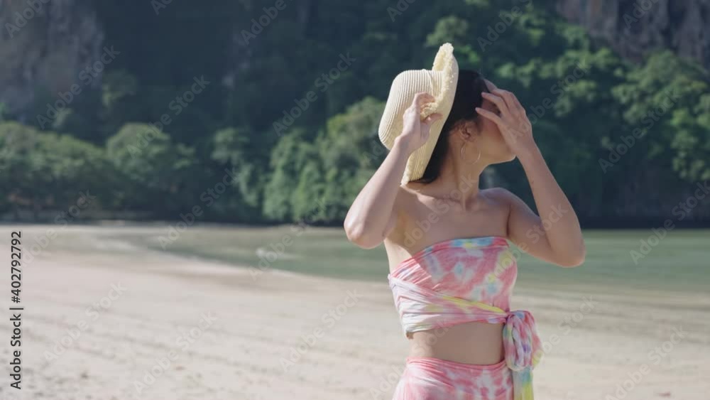 Young pretty asian female walking along Island alone with wind blowing hairs and hat, Travel summer vacation, Asian lady wear straw hat Enjoy summer Holiday, tropical island season hot sunny weather Young pretty asian female walking along Island alone with wind blowing hairs and hat, Travel summer vacation, Asian lady wear straw hat Enjoy summer Holiday, tropical island season hot sunny weather